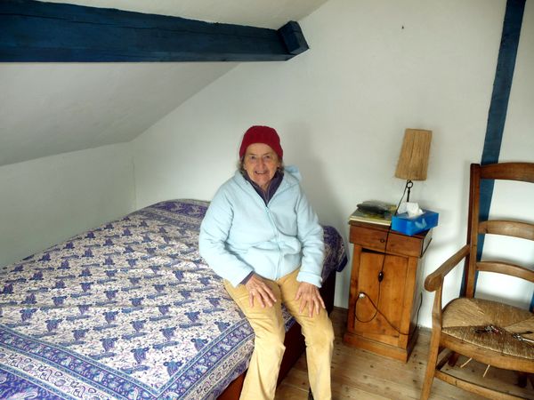 Jacqueline, bonnet rouge sur la tête, pose dans sa chambre